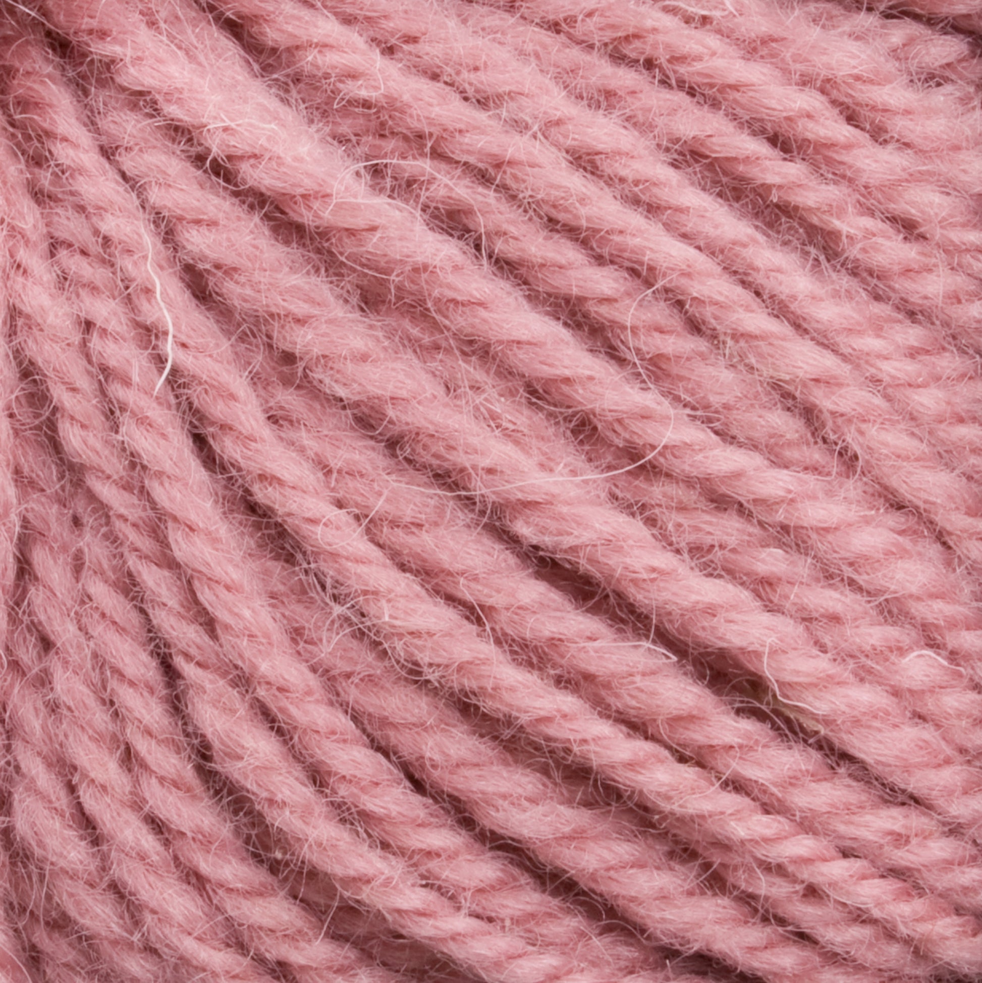 Close-up image of thick, soft Halcyon Deco Rug Wool from Caledonian Dye Works in a vibrant pink hue, twisted together to showcase its texture and fibrous details. This versatile yarn, ideal for crafting deco rug projects, is made from 100% wool.