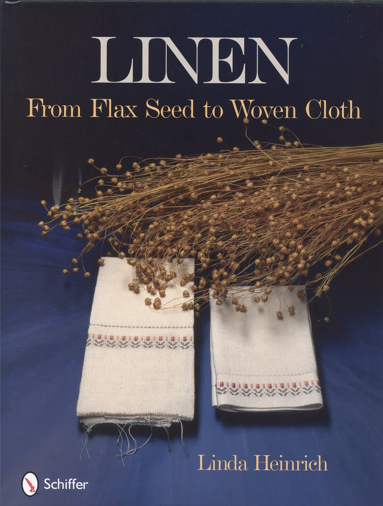 Book cover image showcasing the journey: "Linen From Flax Seed to Woven Cloth" by Linda Heinrich. Two pieces of intricately woven linen cloth with decorative borders are displayed beneath a bundle of harvested flax stalks against a dark blue background. Schiffer Publishing Co. logo on the bottom left.