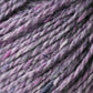 Close-up of Jo Sharp Silkroad DK Tweed by Kingfisher Yarn & Fibre in a blend of purple and grey. This DK weight yarn exhibits a slightly thick and thin texture, seamlessly mixing light and darker shades. The image captures the intricate details of the wool, silk, and cashmere fibers, highlighting the yarn's softness and density.