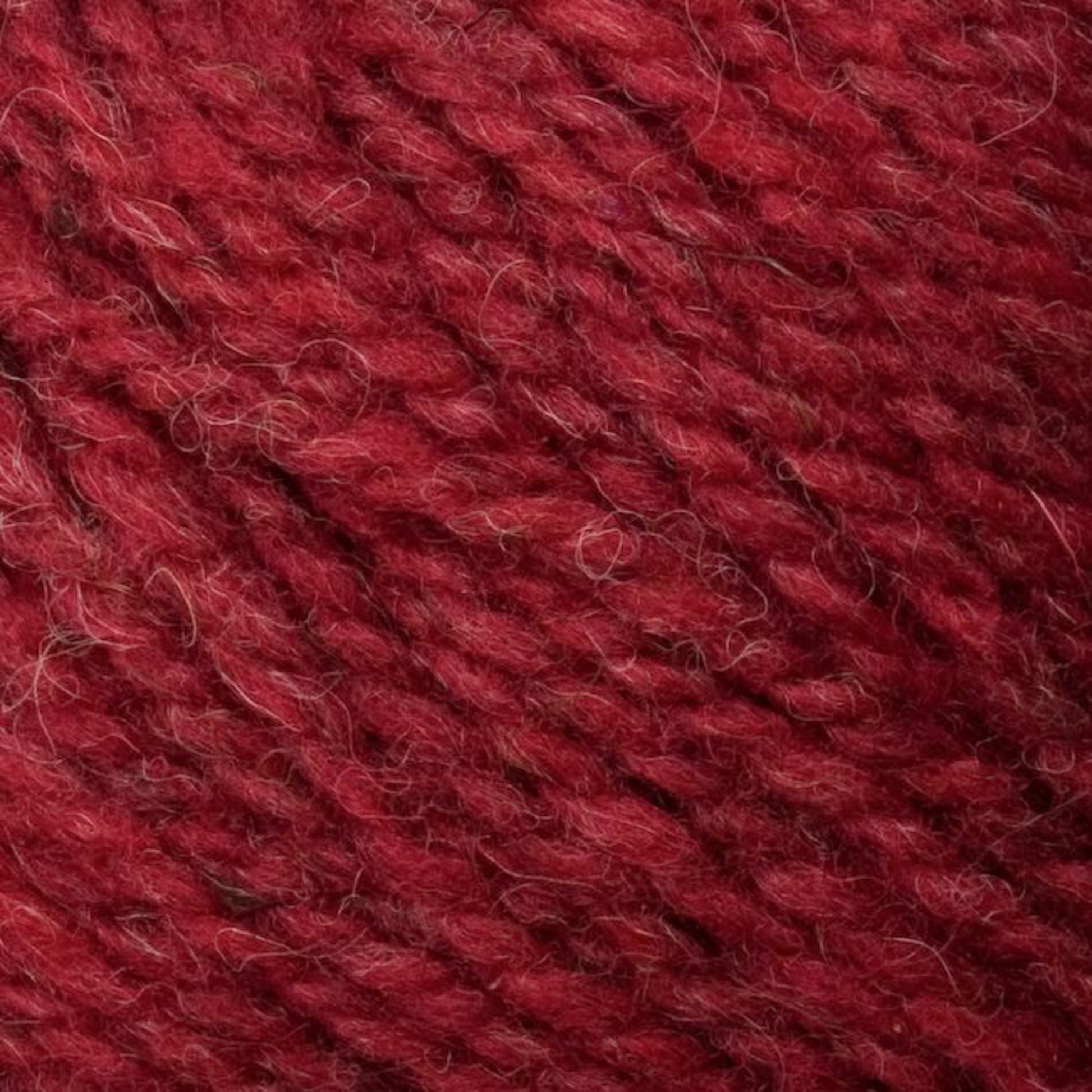 Close-up image of the textured, deep red Bartlettyarns Bartletts Maine Wool - Sport. The yarn appears thick and woolly, with slight variations in the red hue, creating a rich and cozy feel. The fibers are visibly intertwined, highlighting the natural and slightly fuzzy texture of this premium wool.