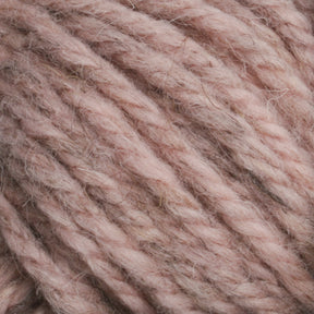 Close-up view of thick, soft Halcyon Yarn Classic Rug Wool in a muted pink color. The yarn appears slightly fuzzy, with a twisted and chunky texture, suggesting it is suitable for cozy, warm projects such as knitted or crocheted garments and accessories. Perfect for weavers seeking hand-dye options or sturdy Rug Wool creations from Caledonian Dye Works.