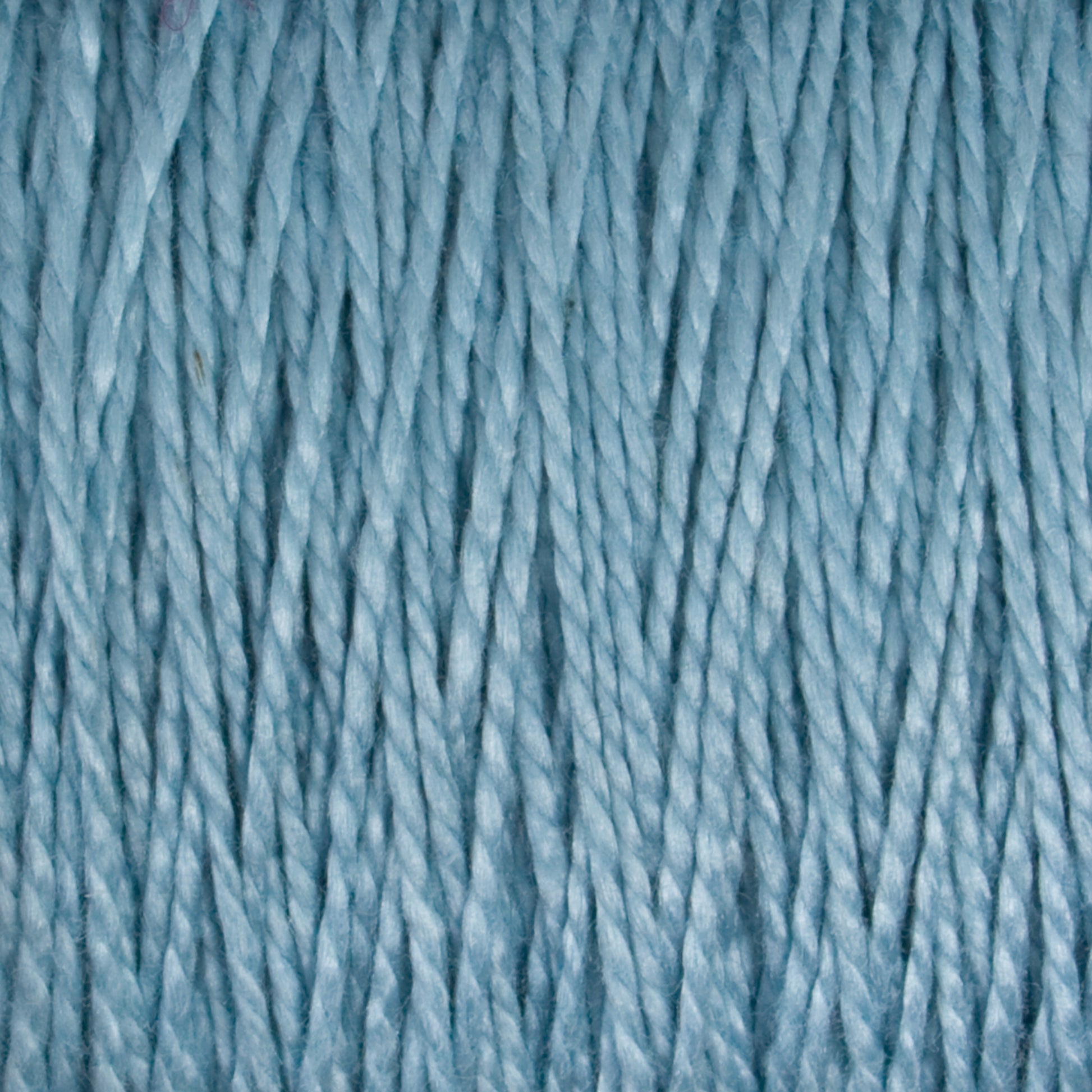 Close-up image of soft sky-blue colored 10/2 Pearl Cotton Yarn from Supreme Corp. The tightly wound fibers have a slight sheen, giving the versatile yarn a smooth and slightly glossy appearance. The texture and gentle color evoke a cozy and soothing feeling while ensuring exceptional colorfastness.