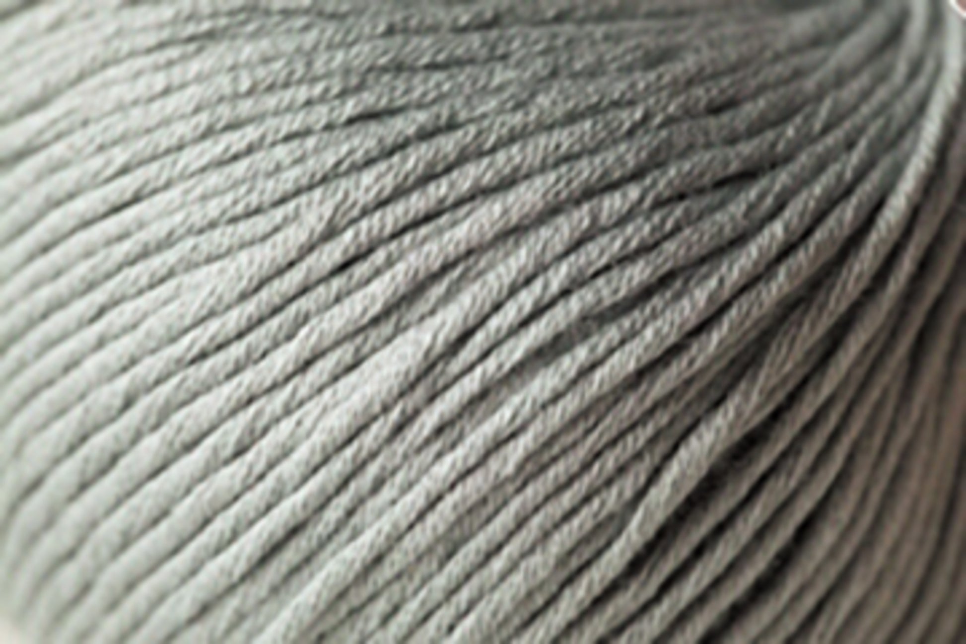 Close-up image of a light green Jo Sharp Soho Summer DK Cotton from Kingfisher Yarn & Fibre, highlighting its soft texture and smooth, twisted strands. The lightweight cotton yarn appears perfect for knitting or crocheting projects, especially those for summer.