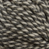 Close-up image of twisted Briggs & Little Tuffy Canadian Sock Yarn strands in a mix of gray and white colors, showing the texture and fiber detail. The yarn is presented in a coiled, circular arrangement, highlighting its intertwined pattern and the varying shades of gray and white. Perfect for cozy winter socks!