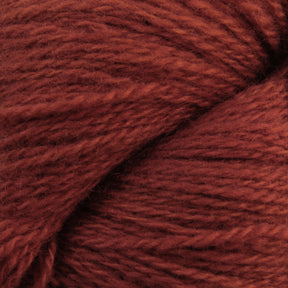 Close-up image of a bundle of Jade Sapphire Cashmere 2-Ply yarn in rust-red. The texture appears soft and slightly fuzzy, with the strands twisting together to form a dense and cozy appearance, perfect for woven accessories. Brought to you by Jade Sapphire Exotic Fibres.