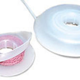 The image displays two EZ Bobs Flip-top Intarsia Bobbins by Bryson Distributing, Inc., both constructed from white plastic. The left bobbin holds a roll of partially unraveled pink braided rope reminiscent of worsted yarn, while the right one is empty but features the same design with a hollow center. Each bobbin has a flat base and a circular shape.