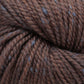 Close-up of Acadia by The Fibre Co. (UK) Ltd, showcasing its brown hues accented by a subtle tweed effect with light gray flecks twisted together. The texture appears soft and slightly fluffy, highlighting the beautifully intertwined strands.