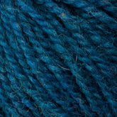 Close-up image of blue and teal sport weight yarn strands, displaying a mix of thick and thin fibrous textures. The intricate details highlight the twisting threads and subtle color variations in this Bartlettyarns Bartletts Maine Wool - Sport yarn.