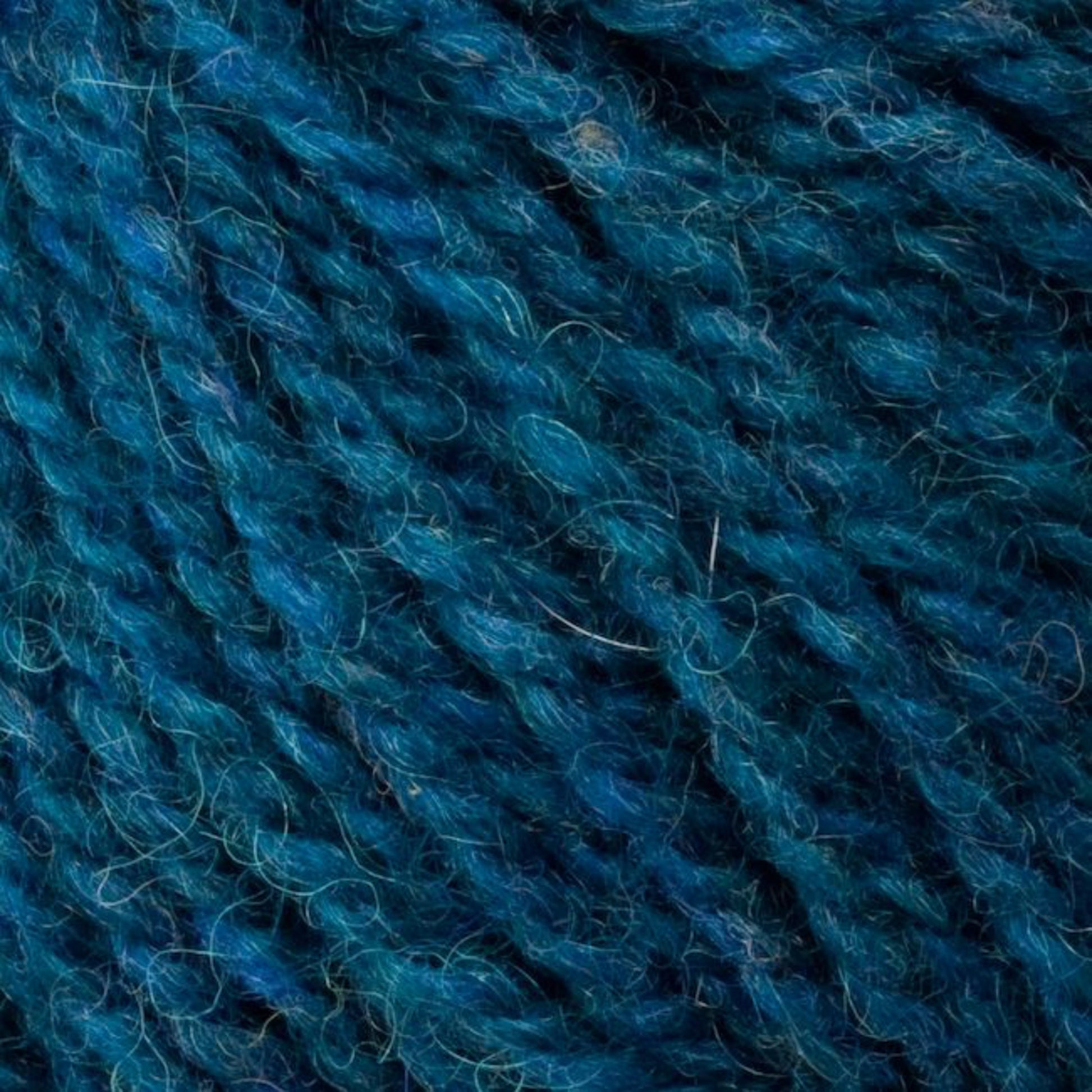 Close-up image of blue and teal sport weight yarn strands, displaying a mix of thick and thin fibrous textures. The intricate details highlight the twisting threads and subtle color variations in this Bartlettyarns Bartletts Maine Wool - Sport yarn.