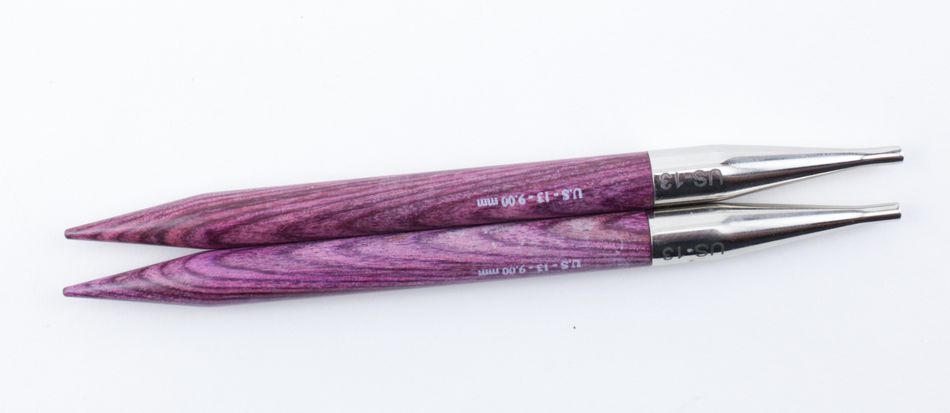 Two Dreamz Interchangeable Knitting Needle Tips by Accessories Unlimited feature purple, grain-textured wooden bodies and silvery metal tips. The smooth joins on the metal portion are engraved with "US 13 - 9.0 mm." Ideal for knitting hats, the needles are shown parallel to each other, with tips pointing to the left.