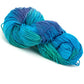 A skein of Great Adirondack Organic DK Cotton from Great Adirondack Yarn Co, Inc., featuring a gradient of vibrant blue and teal shades, hand-dyed and coiled neatly with visible texture.