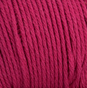 Close-up image of tightly wound Brown Sheep Cotton Fleece yarn. The fibers are neatly aligned and exhibit a soft texture, characteristic of high-quality cotton fleece. The yarn appears to be of medium thickness, perfect for intricate knitting patterns. The color is a rich, deep red.