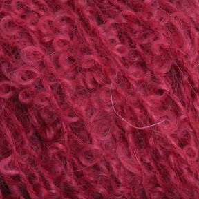 A close-up image of Caledonian Dye Works' Victorian Bouclé Mohair Yarn, featuring a deep red hue with a curly and soft texture, highlighted by intricate loops and fibers.