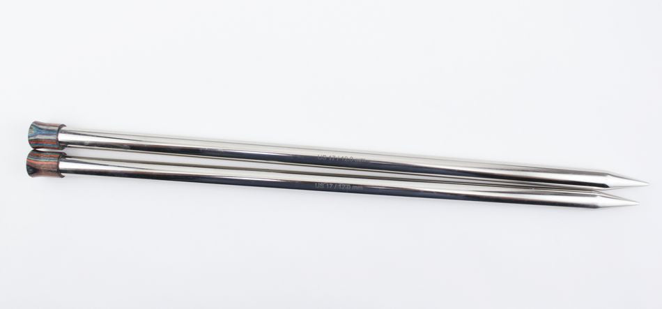 Two Accessories Unlimited Nova Platina Single Point Knitting Needles lying parallel to each other on a white surface. They are slightly reflective, made from hollow brass pipes, and have a flat end on one side with pointed ends on the other for knitting.