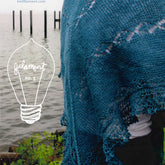 A person stands near a body of water wearing a teal knitted shawl over their shoulders. The backdrop features wooden posts emerging from the water. Text reads "Knit Filament" with a light bulb graphic labeled "Filament No. 3 Summer 2017." This scene epitomizes modern classics in our full-color magazine on knitwear patterns.