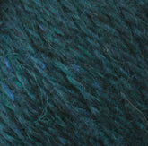 Close-up texture of a ball of dark green and blue variegated Peace Fleece Yarn by Harrisville Designs. The wool and mohair blend fibers interweave to create a soft, fluffy appearance with subtle changes in color throughout.