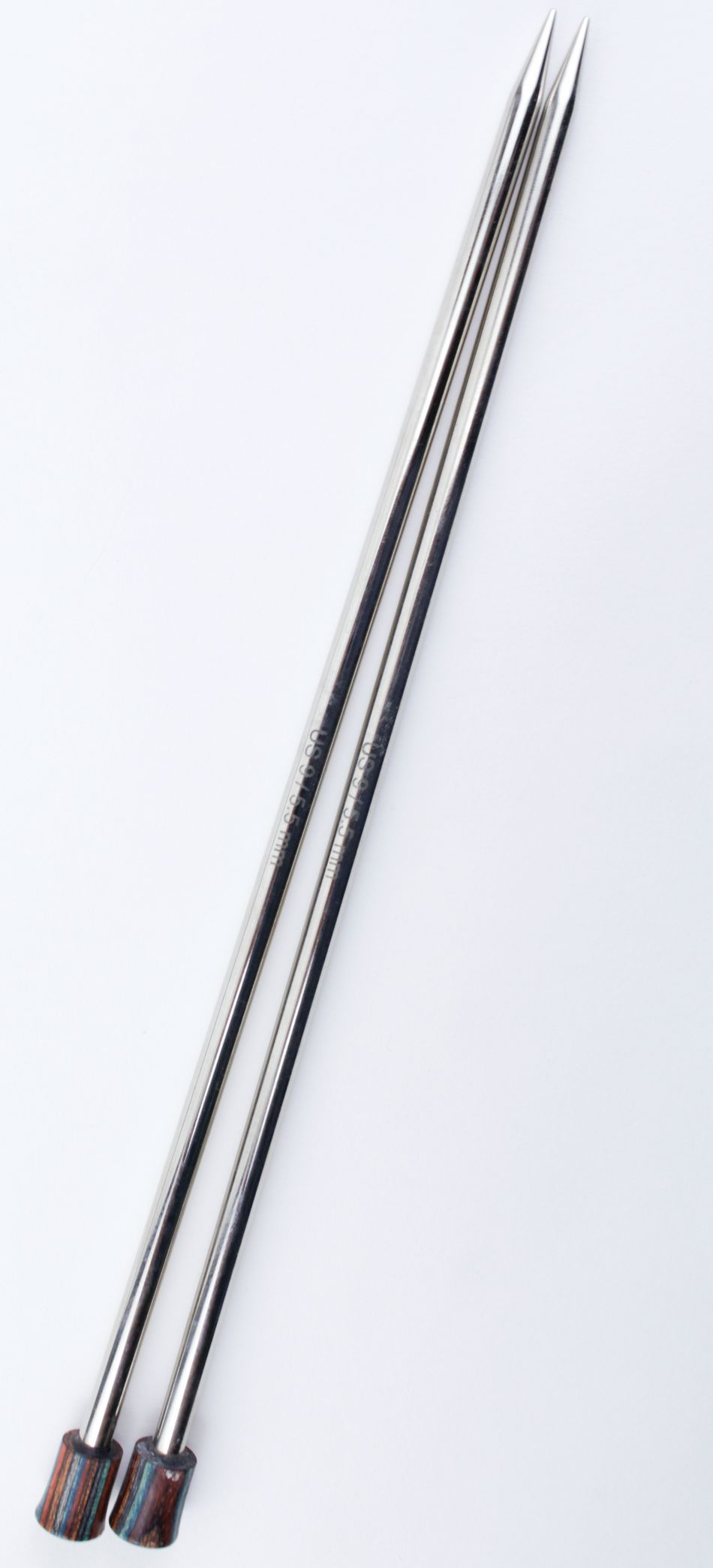 A pair of Accessories Unlimited Nova Platina Single Point Knitting Needles, crafted from hollow brass pipes with pointed ends and wooden stoppers at the opposite ends, are placed parallel to each other against a white background.