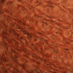 Close-up image of fuzzy, orange Victorian Bouclé Mohair Yarn with a slightly curly and fluffy texture from Caledonian Dye Works' Signature Victorian Collection, showcasing the intricate details of the fibers.