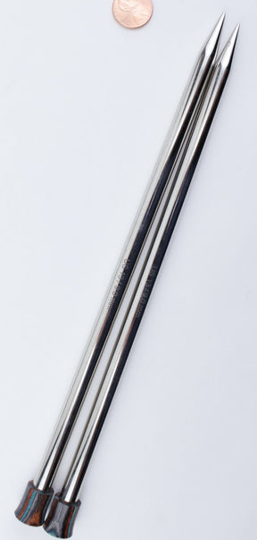 Two metal knitting needles from the Accessories Unlimited Nova Platina Single Point Knitting Needles collection lie parallel to each other on a white surface. The straight needles, with sharp pointed ends and dark-colored caps, have a penny placed near the tips for scale.