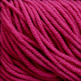 A close-up image of Plymouth Yarn Co.’s Plymouth Select Worsted Merino Superwash fibers in hot pink. The yarn is thick, tightly wound, and showcases its visible texture and fibrous details. The vibrant color stands out, highlighting the stitch definition and exhibiting the intricacies of the material.