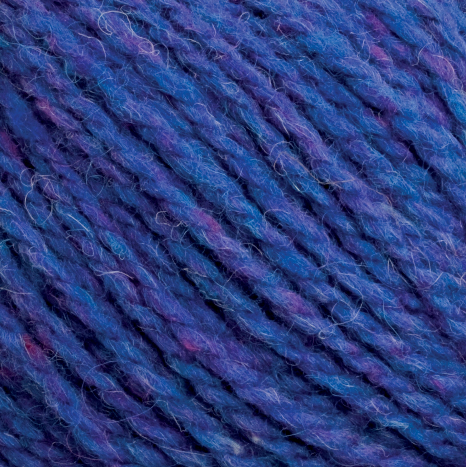 Close-up image of Harrisville Highland - Cones multicolored yarn by Harrisville Designs, featuring various shades of blue and purple with occasional hints of pink. The texture appears soft and slightly fuzzy, showcasing the individual strands twisted together tightly, characteristic of Harrisville Highland's renowned blends.