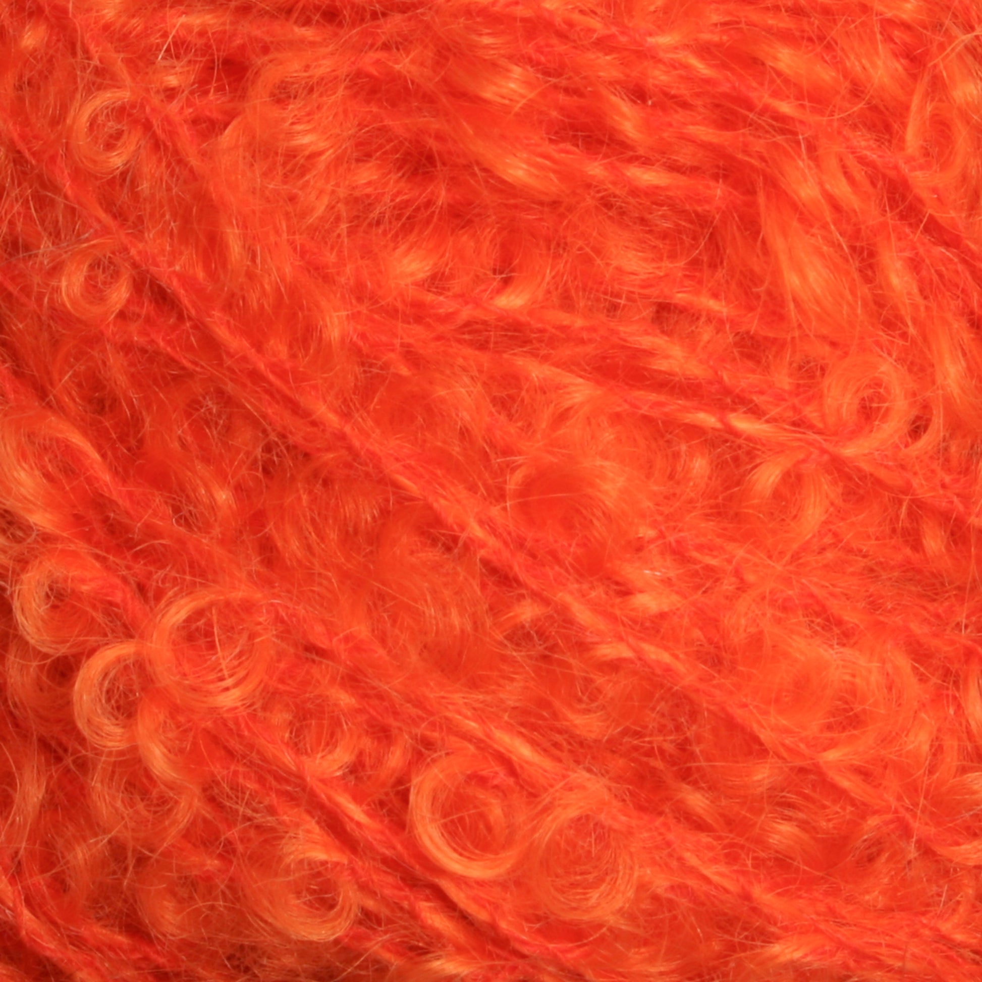 Close-up of the vibrant orange Victorian Bouclé Mohair Yarn from Caledonian Dye Works, featuring a curly and fluffy texture. The soft, densely packed fibers form intricate loops and twists reminiscent of classic bouclé. This weaving yarn's rich color and texture are visually captivating.