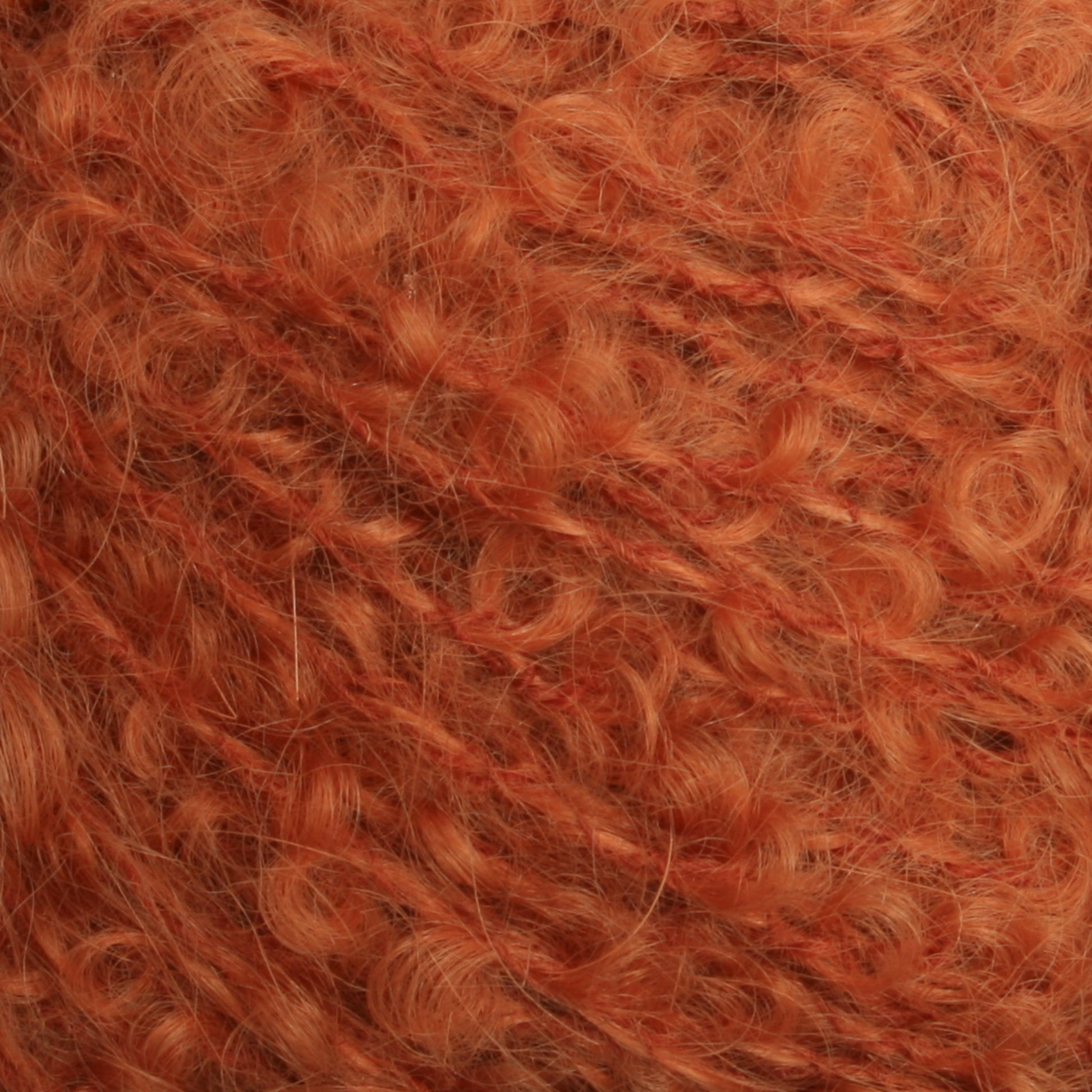 Close-up of a textured surface of Caledonian Dye Works' Victorian Bouclé Mohair Yarn in orange. This luxurious yarn has a soft, fuzzy appearance with fibers that vary slightly in thickness, creating a cozy and warm look. The image emphasizes the detailed, intricate patterns formed by the individual strands of this exquisite mohair bouclé.