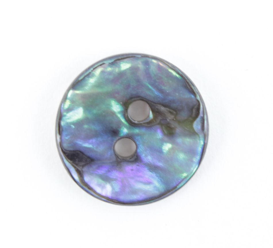 A close-up of a round, iridescent Mexican Abalone Button by Skacel with two holes in the center. The button's surface features shimmering shades of blue, green, and purple, creating a pearlescent effect reminiscent of Natural Mexican Abalone buttons. The background is plain white.