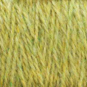 Close-up of Harrisville Designs' Harrisville Shetland Yarn - Unwashed Cones in a soft, yellowish-green hue. The twisted strands reveal shades of yellow, green, and hints of white, creating a textured and slightly fuzzy appearance. Ideal for Fair Isle knitting projects and lightweight blankets, the image showcases the detailed fibers and consistent thickness.