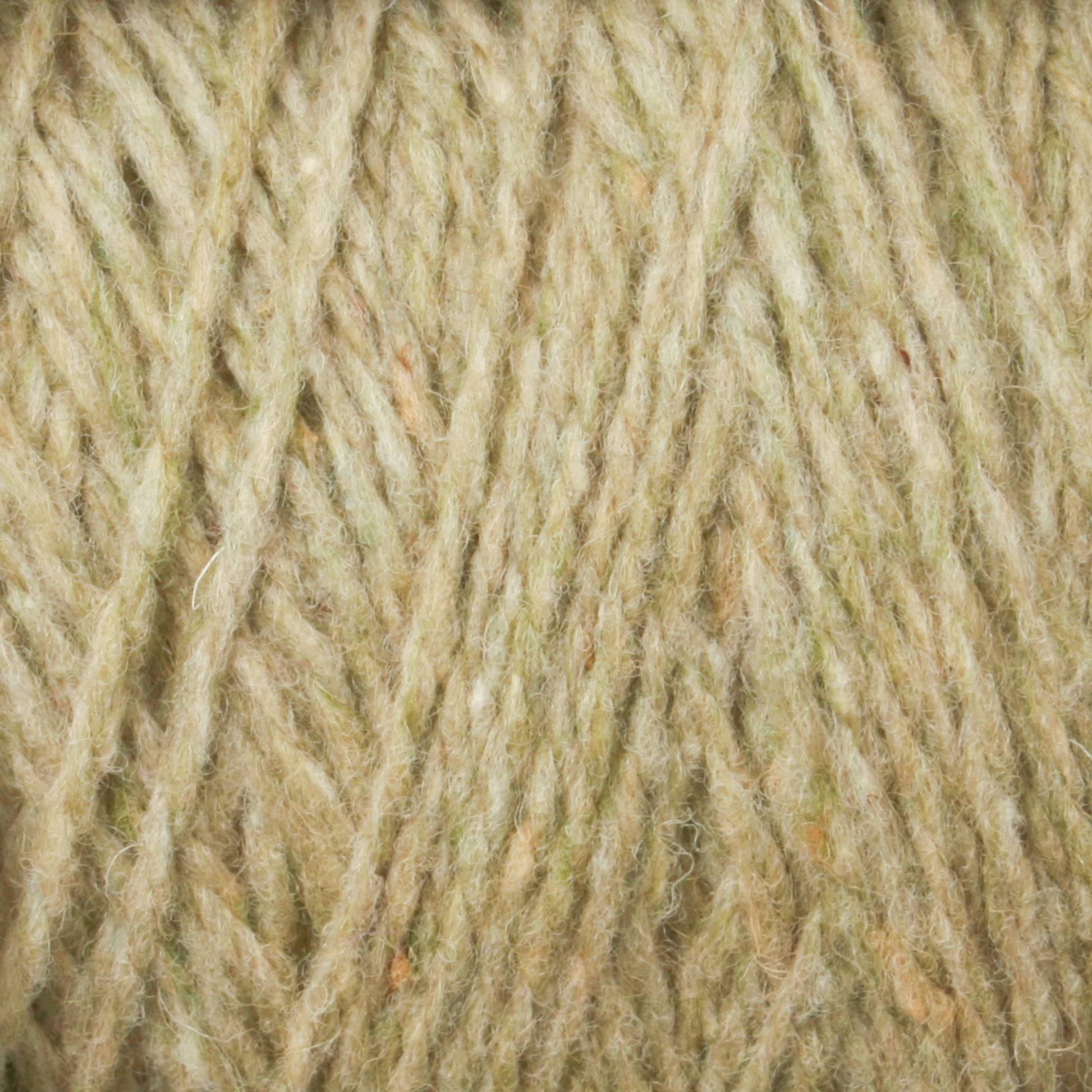 Close-up image of Harrisville Shetland Yarn - Unwashed Cones by Harrisville Designs, featuring textured, multicolored strands in various shades of beige, brown, and light green. The soft and slightly fuzzy fibers intersect at different angles to form a dense, intricate pattern reminiscent of Fair Isle knitting designs.