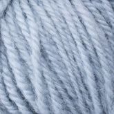 A close-up image of Halcyon Deco Rug Wool by Caledonian Dye Works, showcasing the texture and twist of the pale blue fibers. The 100% wool yarn appears soft and fluffy, suitable for knitting or crocheting. The strands are thick and woven tightly together.