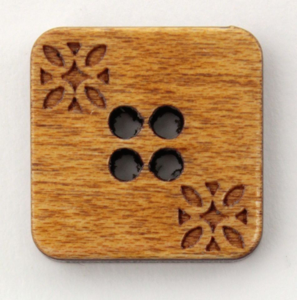 The Wood Square 3/4" Button by Buttons Etc. is a quaint, square wooden button with gently rounded corners and four circular holes in the center. Diagonally opposite corners are adorned with a delicately etched floral design, while the visible grain of the wood enhances its rustic charm.