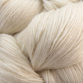 Close-up view of soft, off-white Malabrigo Yarn's Merino wool, coiled in dense skeins. The texture shows fine, slightly uneven strands, creating a plush and cozy appearance—perfect for crafting delicate Malabrigo Lace knitted shawls.