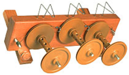 The Majacraft Tensioned Lazy Kate, manufactured by Majacraft Co., is elegantly crafted from rimu wood and features three spools, each mounted on a rod for holding and unwinding yarn. Metal holders are positioned above each spool to guide the yarn. This sophisticated device has a rectangular wooden base and incorporates a scotch tension mechanism.