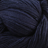 A close-up image of Malabrigo Lace by Malabrigo Yarn in dark blue. The fibers appear soft and neatly wound, showcasing intricate textures and subtle variations in the shade of blue. Ideal for knitted shawls, the yarn is tightly coiled, creating a rich and detailed pattern reminiscent of handcrafted elegance.