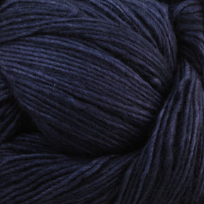 A close-up image of Malabrigo Lace by Malabrigo Yarn in dark blue. The fibers appear soft and neatly wound, showcasing intricate textures and subtle variations in the shade of blue. Ideal for knitted shawls, the yarn is tightly coiled, creating a rich and detailed pattern reminiscent of handcrafted elegance.