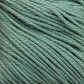 Close-up of light sage green Cascade Ultra Pima Cotton Yarn strands tightly wound together. The texture of the Peruvian Pima Cotton yarn from Cascade Yarns is visible, revealing a smooth yet slightly fibrous appearance. The color is consistent throughout the yarn, giving a soft hand and calming feel.