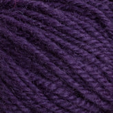 Close-up of the soft, tightly wound Halcyon Deco Rug Wool yarn in a rich, deep purple color. The individual strands are clearly visible, showcasing a textured and slightly fuzzy surface. This 100% wool yarn by Caledonian Dye Works is perfect for versatile projects.