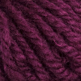 Close-up image of Halcyon Yarn Classic Rug Wool from Caledonian Dye Works. The thick, purple wool fibers are tightly spun, showcasing a visible texture and a slight sheen under the light. Hand-dyed to achieve a rich color, this yarn's soft appearance makes it ideal for knitting or crocheting cozy garments, as well as perfect for weavers seeking high-quality material.