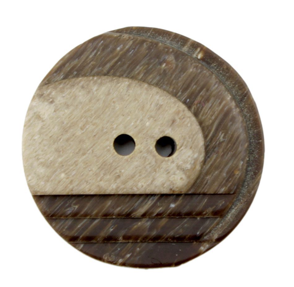 A close-up of Dill Buttons of America, Inc's Two Tone Button reveals a round, two-holed button made from a textured, mottled material that mimics the appearance of stone or coconut shell. This 1" button features a blend of light and dark brown hues with a striped pattern, creating an organic two-tone shading effect.