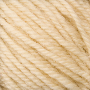 Close-up image of a bundle of Halcyon Deco Rug Wool from Caledonian Dye Works. The soft, cream-colored yarn has a slightly fuzzy texture. Made from 100% wool, it is tightly wound, showcasing the individual strands and fibers intertwined together.