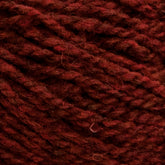 Close-up view of deep red wool yarn, tightly wound in a coil pattern. The Harrisville Designs Shetland Yarn - Unwashed Cones texture appears soft and slightly fuzzy, with visible fibers and a rich, warm color—perfect for crafting lightweight blankets or Fair Isle knitting designs.