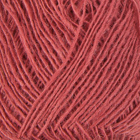 Close-up of a ball of coral-colored Einband Lopi yarn by Berroco, Inc. The yarn strands are neatly wound, creating a textured pattern. The threads appear soft and slightly fuzzy, indicative of a natural fiber perfect for stranded colorwork.