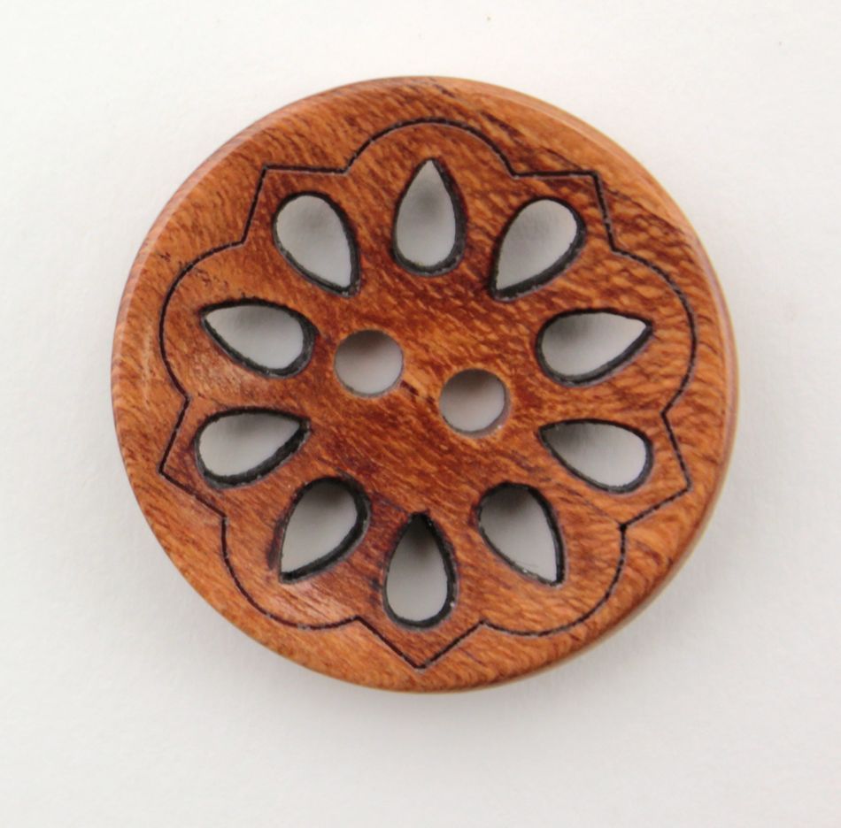 Introducing the Wood Filigree Button by Buttons Etc. – a round wooden accessory adorned with a delicate, floral cutout pattern. This charming button features four central holes for sewing and an elegant, flower-like filigree design with petal-shaped cutouts around its perimeter.