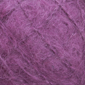 Close-up image of a ball of Victorian Brushed Mohair Yarn from Caledonian Dye Works, with luxurious and fuzzy texture. The large skein showcases strands intertwined in a slightly disordered manner. The yarn appears soft and fluffy, with fibers sticking out, giving it a textured and slightly frizzy appearance reminiscent of traditional Victorian yarns.