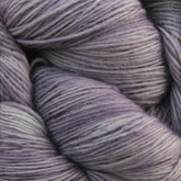 Close-up of softly twisted skeins of Malabrigo Lace by Malabrigo Yarn in variegated shades of light gray and lavender. The finely spun merino wool fibers create a smooth and slightly fuzzy texture. The subtle color gradient adds a serene and calming effect to the image, perfect for knitted shawls.