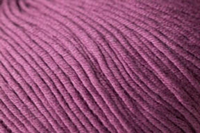 Close-up image of Jo Sharp Soho Summer DK Cotton from Kingfisher Yarn & Fibre. The purple fabric features a ribbed pattern and tightly woven threads, creating a uniform surface across the lightweight cotton material. The color appears consistent, with subtle variations due to lighting.