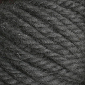 Close-up image of Halcyon Yarn Classic Rug Wool | Skein by Caledonian Dye Works. The thick, dark gray yarn features a slightly fuzzy texture and is tightly twisted in plies. The fibers appear soft and well-defined, making it ideal for knitting or crocheting projects. Perfect for weavers looking to incorporate this high-quality rug wool into their hand-dye creations.