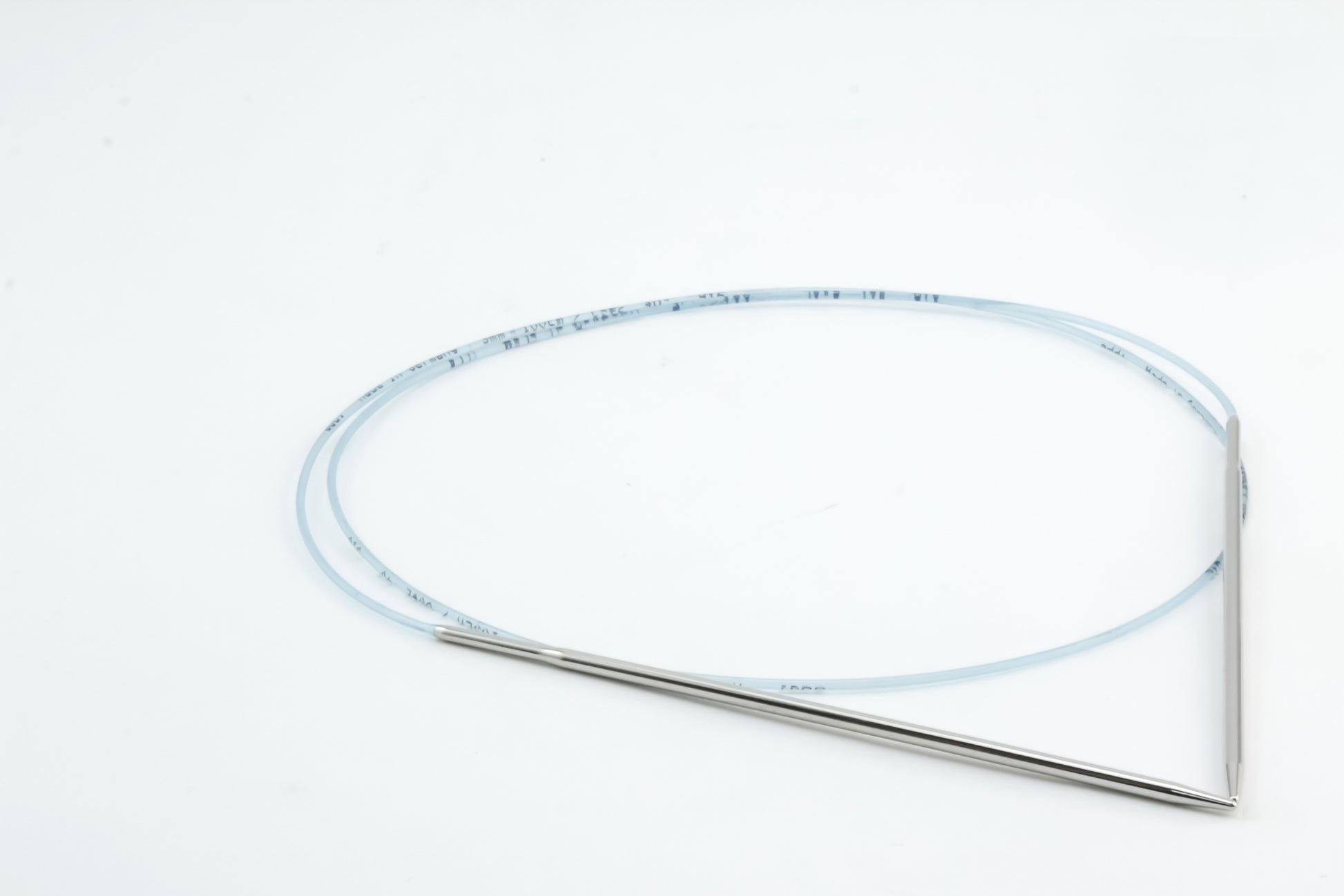 A pair of Skacel's Addi Turbo Circular Knitting Needles, featuring silver short circular needles linked by a flexible, translucent cord, displayed in a triangular shape against a white background.