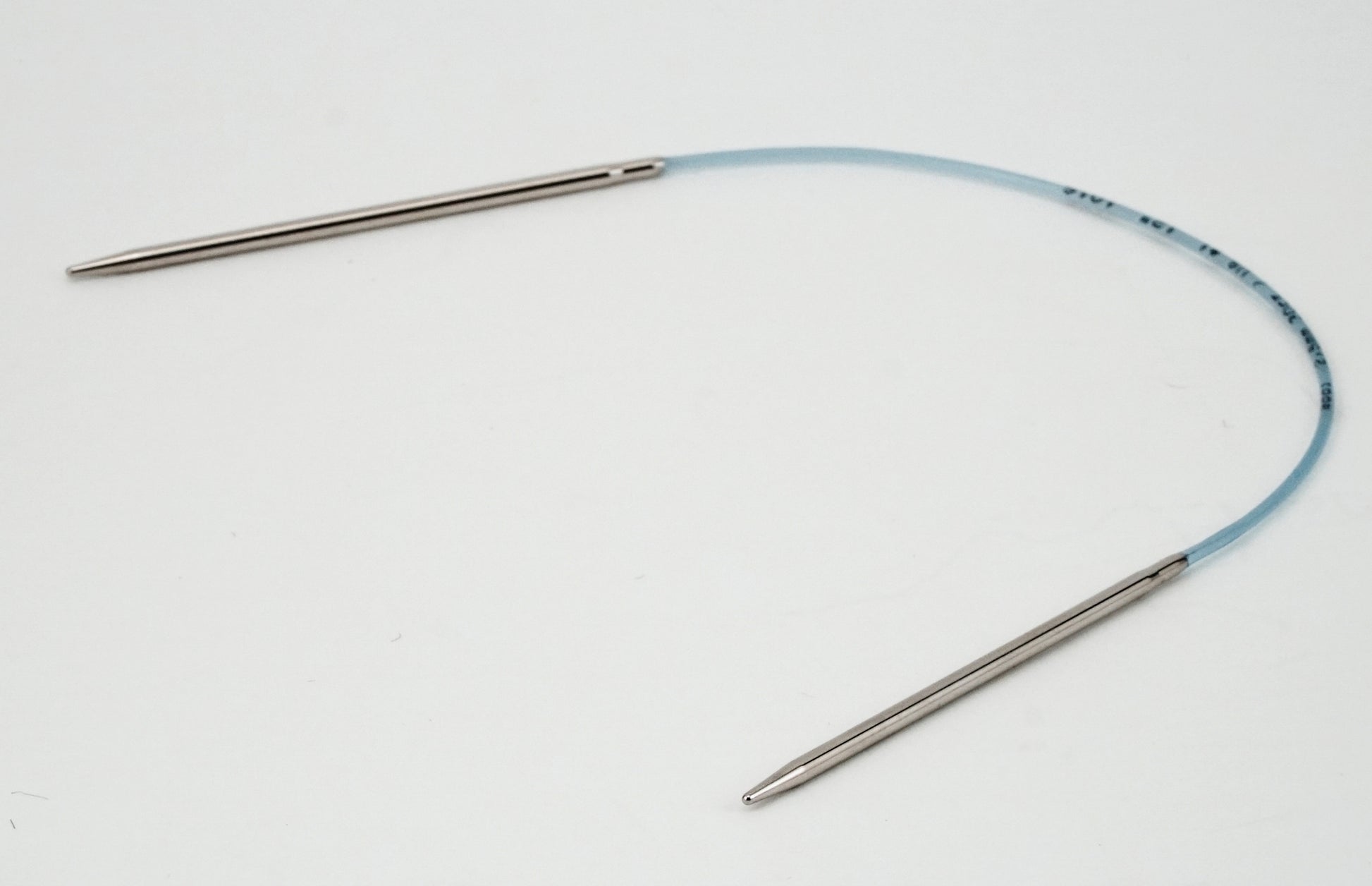 A pair of Skacel Addi Turbo Circular Knitting Needles with metal tips connected by a flexible blue cable are displayed against a plain white background. The slightly curved cable forms an open loop, ideal for knitting projects like cuffs, collars, and doll clothes.